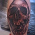 Tatuaggio grande sul braccio il teschio con l'occhio nella bocca