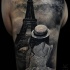 Tatuaggio alla spalla colorato dall'aspetto fantastico della donna che guarda la torre Eiffel