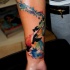 Flock of flying dark black birds tattoo on forearm with watercolor stains
