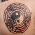 Tatuaje en la espalda, yin yang y notas musicales