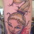 Funny cartoon like severed head of Barby doll tattoo on forearm