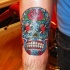 Tatuaje en el antebrazo,
calavera de azúcar estupenda, estilo de dia de muertos