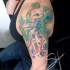 Funny octopus with green and blue paint drips shoulder tattoo in watercolor style