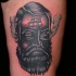 Tatuaje en el muslo,  rostro negro de un hombre con barco en la frente