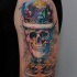 Funny smiling skeleton with monarchy crown colored tattoo on shoulder with watercolor elements