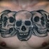 Gray washed style detailed chest tattoo of various skulls