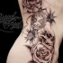 grande rose con cranio e orologio tatuaggio sulle costolette