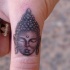 eccezionale piccolo inchiostro grigio faccia di Budda tatuaggio su dito