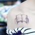 Tatuaje en el hombro, dibujo pequeño negro blanco de 
 manos con libro
