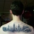 Hausgemachtes Aquarell schwarzes Tattoo am oberen Rücken mit der Nacht Stadt Sehenswürdigkeiten