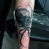Horror style black ink forearm tattoo of spider with human skull