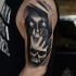 Horror style black ink shoulder tattoo of creepy woman face with hand skull
