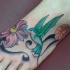 bel uccello  kolibri  su fiore tatuaggio colorato sul  piede