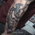 Illustrative style black ink arm tattoo of human hand with flower and scissors