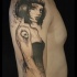 Illustrative style black ink shoulder tattoo of woman stylized with skull