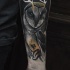 Illustrative style colored forearm tattoo of owl with horns