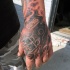 Illustrative style colored hand tattoo of human skull with helmet