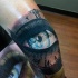 Illustrative style colored leg tattoo of woman eye with clock