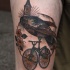 Illustrative style colored thigh tattoo of bird with bicycle