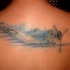 Illustrative style colored upper back tattoo of flying plane