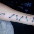 Tatuaje de puntadas  azules en el antebrazo