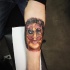 Interesting looking colored forearm tattoo of human face with sun glasses
