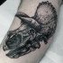 Large black ink engraving style antic dinosaur skull tattoo on leg muscle