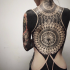 Large blackwork style whole back tattoo combined with ornamental flowers