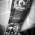 Lifelike breathtaking detailed forearm tattoo of cute panda bear eating grass
