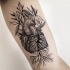Tinta negra de Linework pintada por Michele Zingales tatuaje de bíceps del corazón humano con plantas