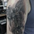 Tatuaje negro blanco en el brazo,
 ángel intrepido que mata a la serpiente