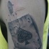Tatuaje en el brazo, naipe con símbolo as de picas y bala