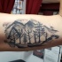 Tatuaje en el brazo, montañas con árboles, dibujo simple negro blanco