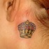 Tatuaje de corona multicolor detrás de la oreja