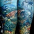 Tatuaje en el antebrazo, diseño muy realista, océano impresionante con varios peces