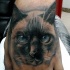 Tatuaje en la muñeca de un gato realista encantador.