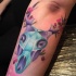 Tatuaje en el antebrazo,  cráneo magnífico multicolor con flores diminutas