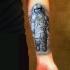 Tatuaje en el antebrazo, astronauta gris simple con tierra reflejada en el casco