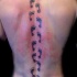 Tatuaje  de camino de huellas  a lo largo de la columna vertebral