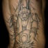 Tatuaje en el costado, dios Anubis y pirámides, dibujo simple negro blanco