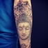 Medium size dot style stone Buddha statue tattoo on forearm combined with ornamental flowers