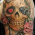 Mexican traditional shoulder tattoo of human skull stylized with flowers and butterflies