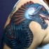 Modern illustrative style colored shoulder tattoo of evil fantasy dragon