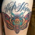 Modern traditional style colored thigh tattoo of big butterfly stylized with human skull and lettering