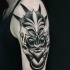 Misterioso tatuaje estilo brazo blackwork de cara demoníaca por Michele Zingales