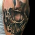 Mystical black and white human skull tattoo on shoulder stylized with clock