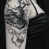 Mystical looking black ink shoulder tattoo of human skull with tree and mountains