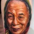 Natural looking colored thigh tattoo of old Asian man portrait