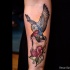 Neo traditional style colored forearm tattoo of small owl with woman hand and rose