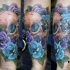 New school style colored forearm tattoo of human skull with various colored roses